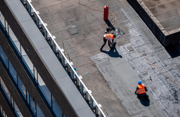 commercial roof maintenance-arial view of 2 roof techs installing roofing materials on commercial roof