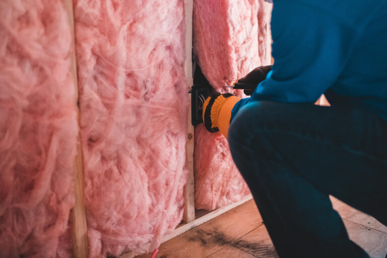 attic insulation-fiberglass insulation being installed in an attic