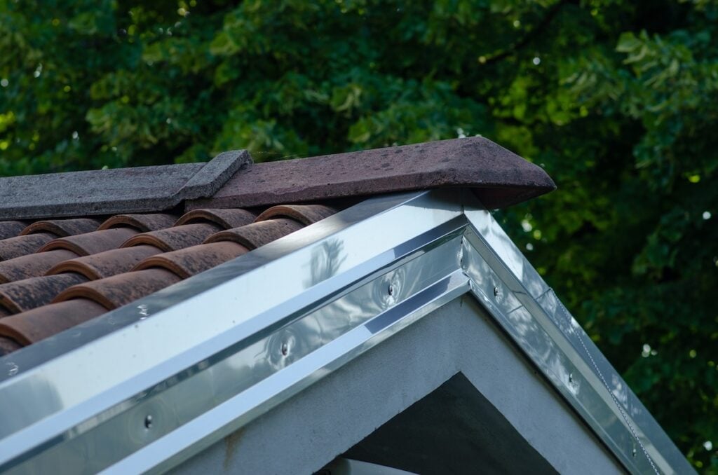 roof building: cornice with galvanized steel sheet, detail of the house on the part of the double-sided roof with ridge tiles.