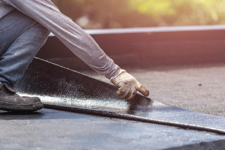 roof membrane-close up of man installing rubber roof membrane on flat roof