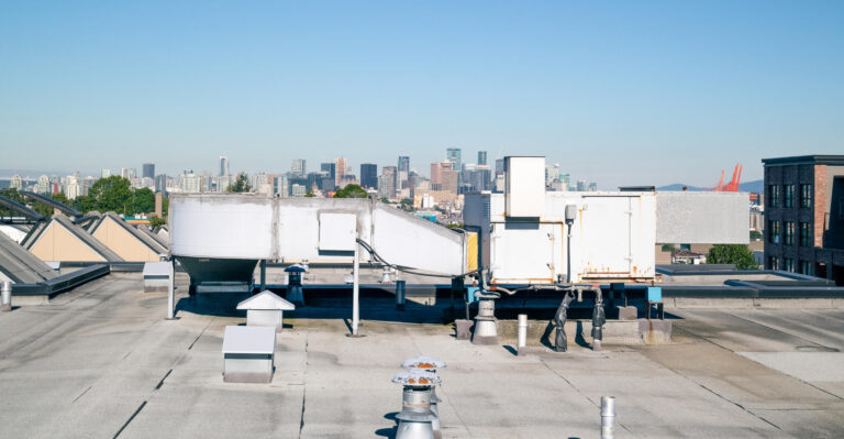 types of flat roofs-bitument roofing on flat roof with city in the background