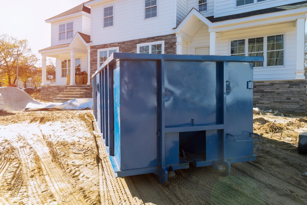 Blue dumpster, recycle waste and garbage bins near new construction of apartment houses building