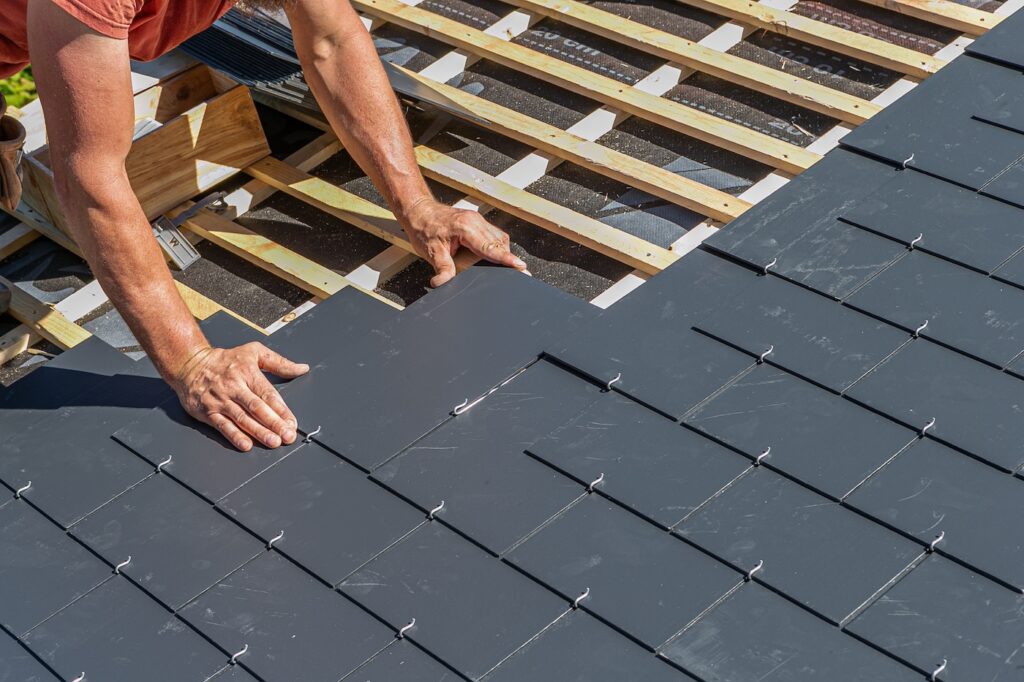 Close-up of the gesture of the hands of the roofer for the installation of the slates.