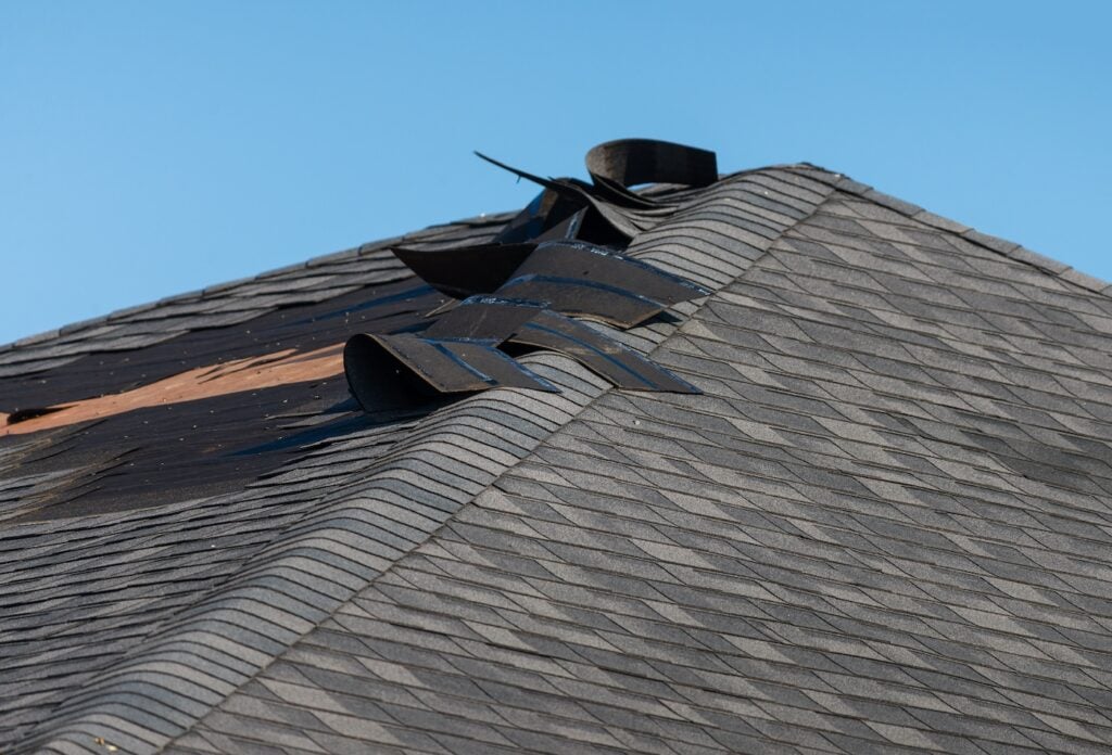 handyman using nail gun to install shingle to repair roof