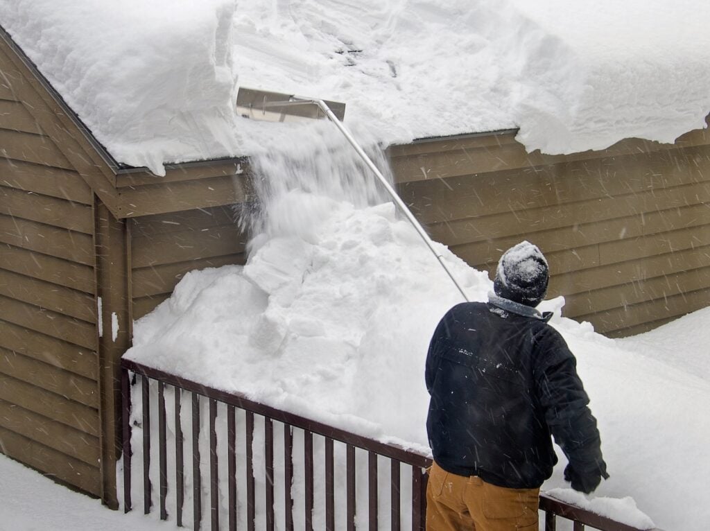 removing heavy snow from shed with rake