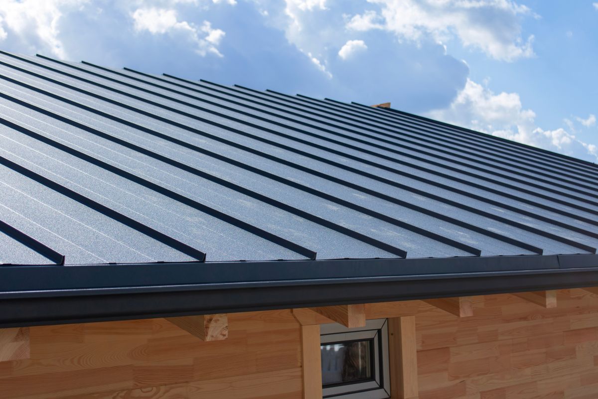 Dark gray standing seam metal roof and black gutter system on a building