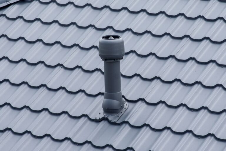 Plastic roof vent pipe on gray metal tile roofing